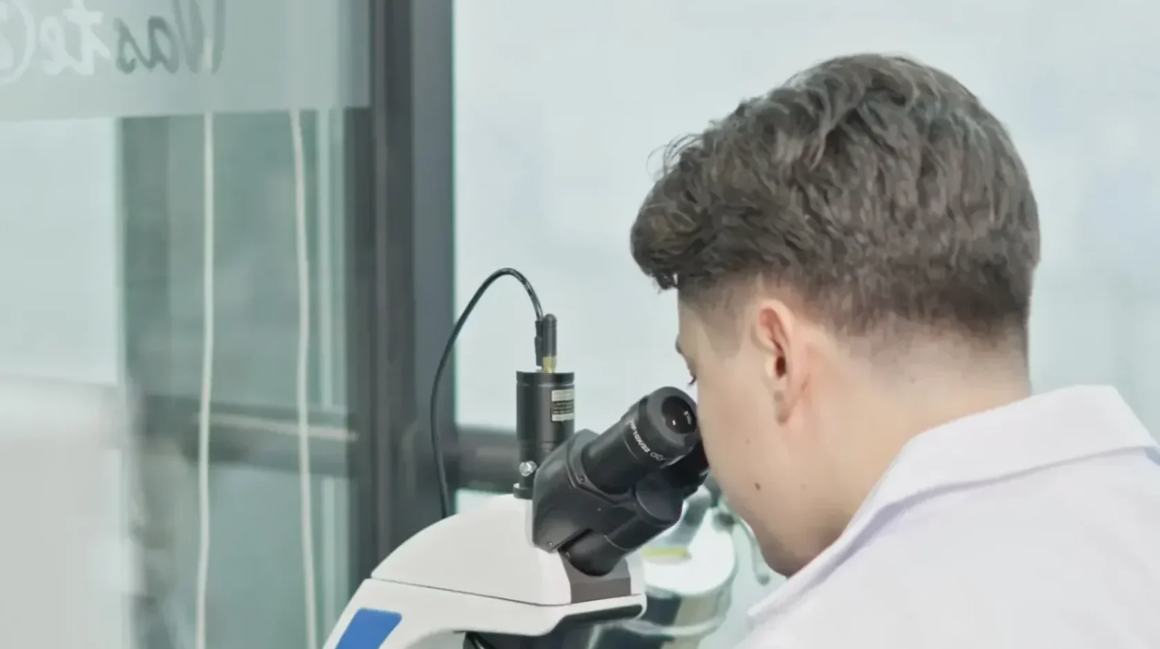 A Waste2Wear scientist examining a sample under a microscope in the lab